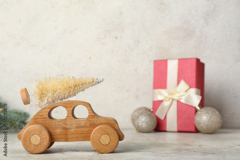 Wooden toy car with Christmas tree on light background