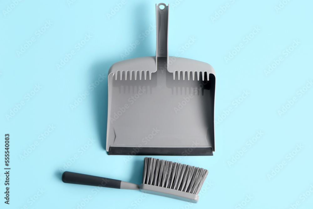 Dustpan and brush on color background