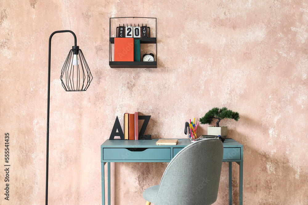 Interior of stylish office with workplace, books and lamp