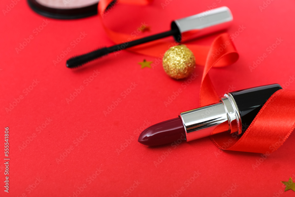 Composition with cosmetics and Christmas decor on red background, closeup