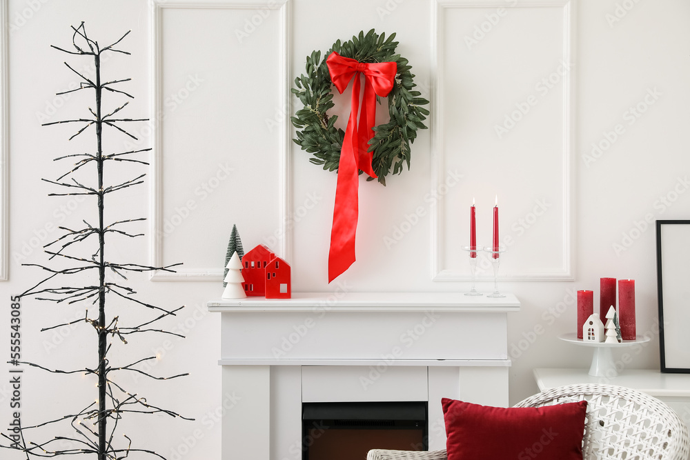 Christmas wreath with bow hanging on light wall in living room