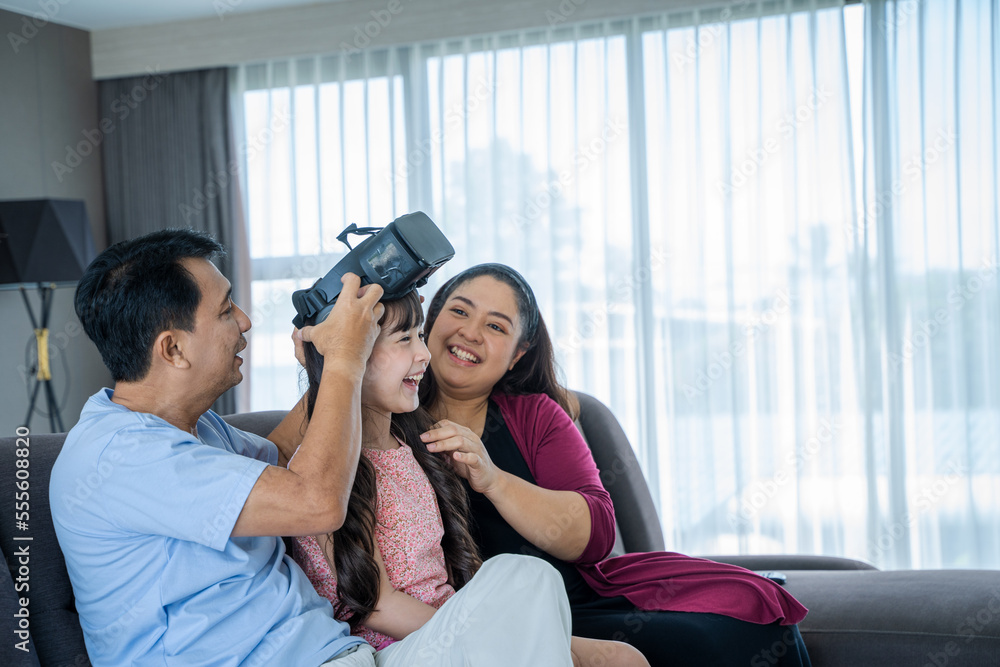 Father and mother with daughter playing with virtual reality goggles at home,VR headset,Modern techn