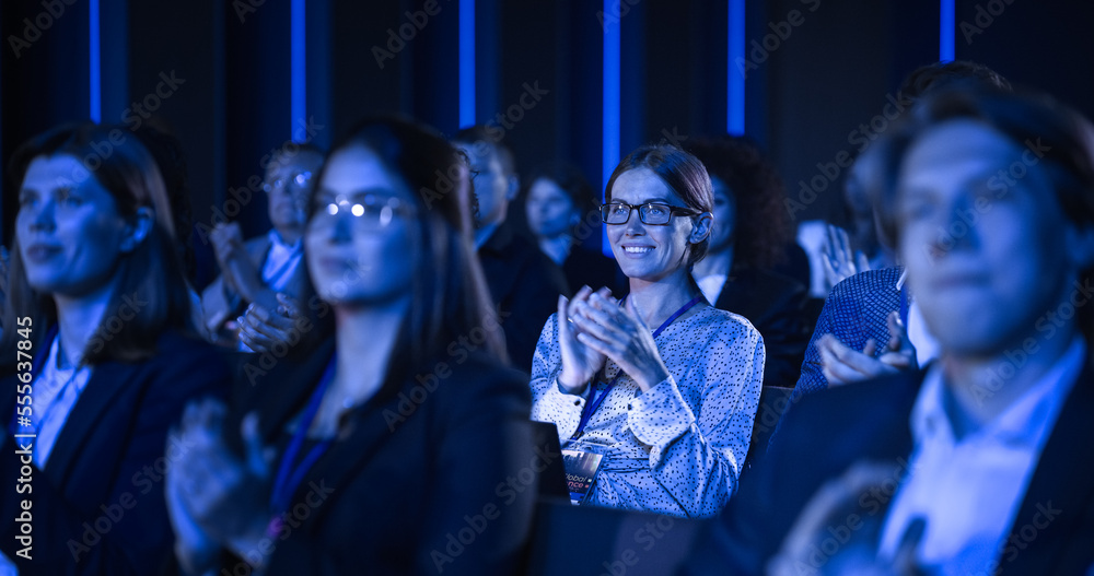 Audience Full of Business People Clapping in Dark Conference Hall During an Inspiring Keynote Presen