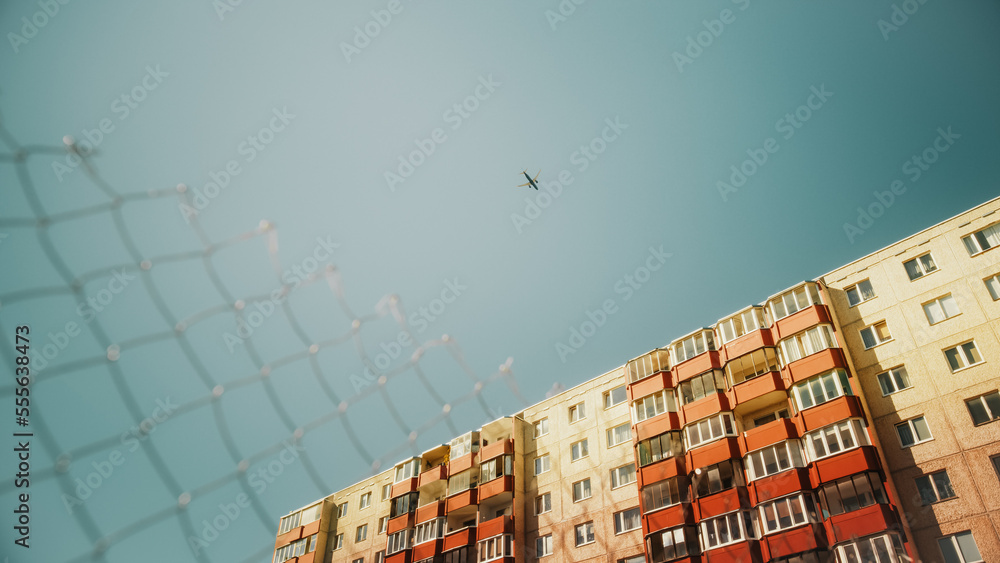 Commercial Airplane Flying Over a Suburbian Part of an Eastern European City on a Sunny Day with Cle