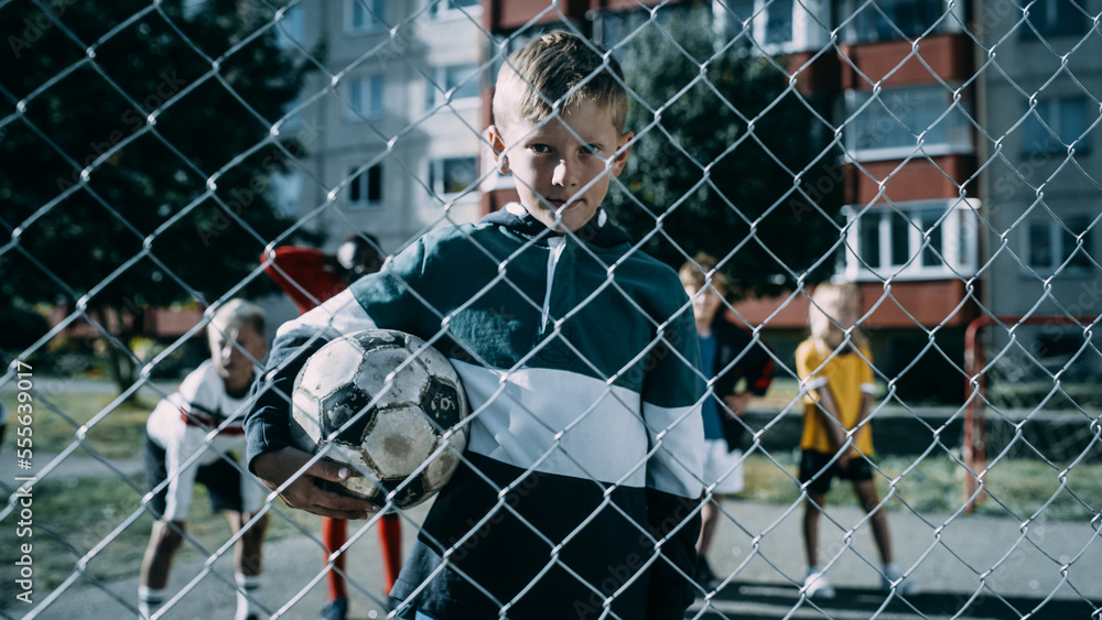 Portrait of a Cute Boy Holding a Soccer Ball on an Outdoors Field in the Neighborhood. Young Footbal