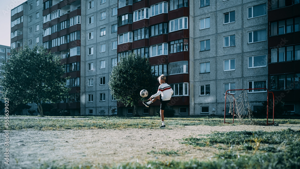 Young Caucasian Kid Playing with Ball in the Neighborhood. Boy Practicing Soccer Drills, Doing Kick-