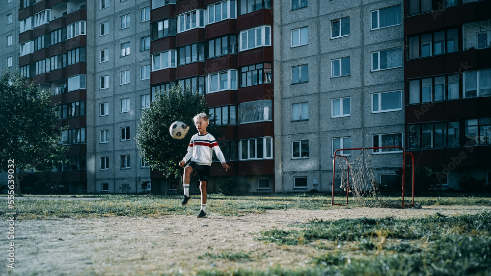 Young Caucasian Kid Playing with Ball in the Neighborhood. Boy Practicing Soccer Drills, Doing Kick-