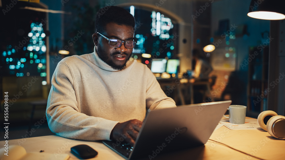 Portrait of a Handsome Black Project Manager Making a Video Call on Laptop Computer in an Evening Of