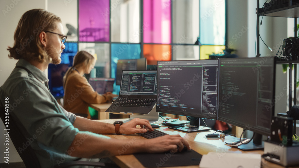 Caucasian Man Coding on Personal Computer and Laptop Set Up In Stylish Office. Professional Programm