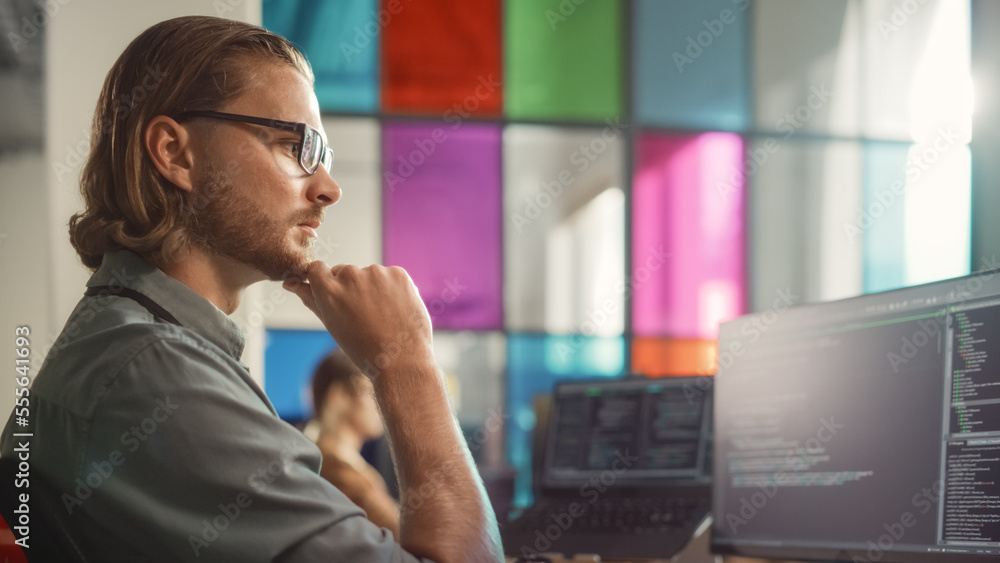 Male Senior Software Engineer Coding on Desktop PC With Multiple Monitors Setup and Laptop Aside in 