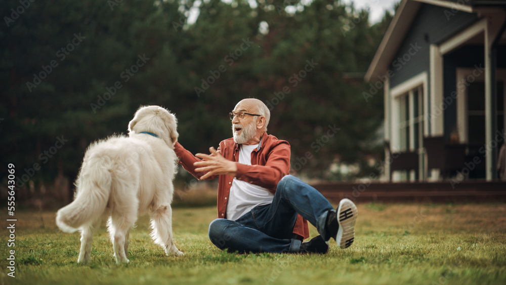 一个快乐的成年男子与一只宠物金毛寻回犬在户外享受时光的肖像，抚摸着一只顽皮的小狗