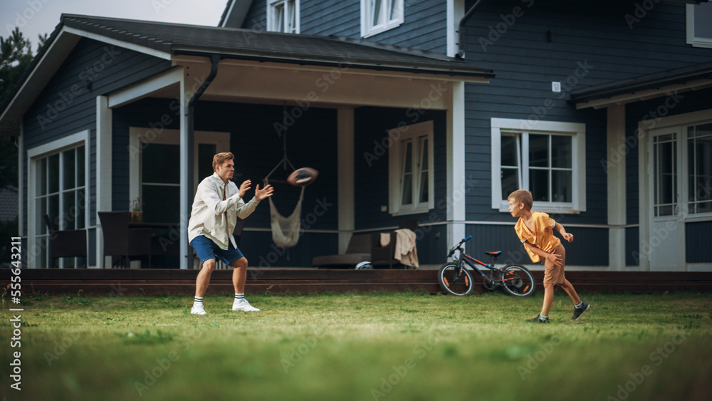 Young Athletic Father Playing Ball with His Young Son. Dad Teaching the Boy to Play American Footbal