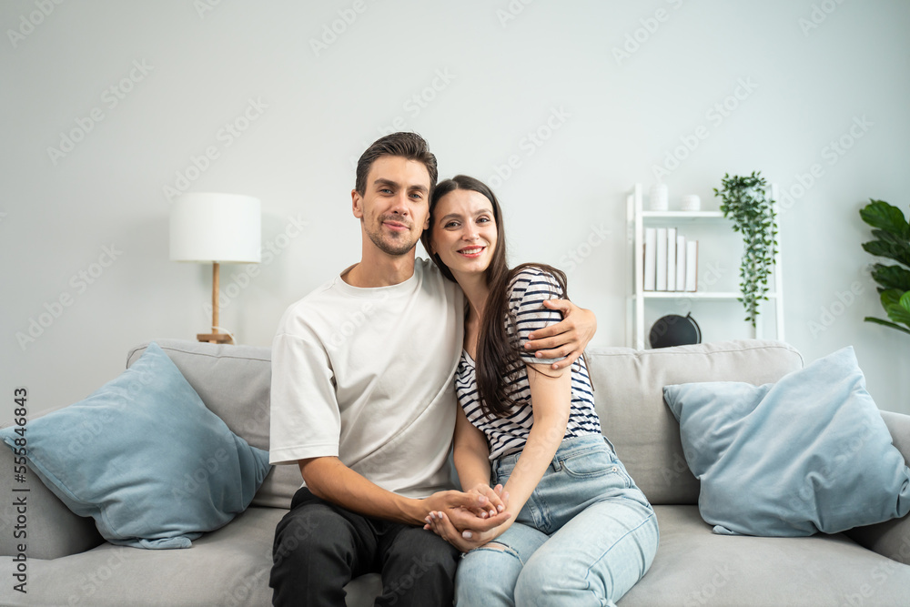 Portrait of Caucasian couple sitting on sofa in living room at home.