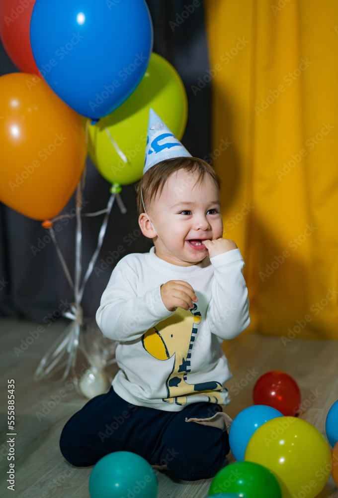 Happy baby boy with bunch of balloons. First birthday baby boy party.