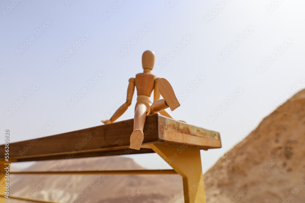 Wooden mannequin on fence in desert