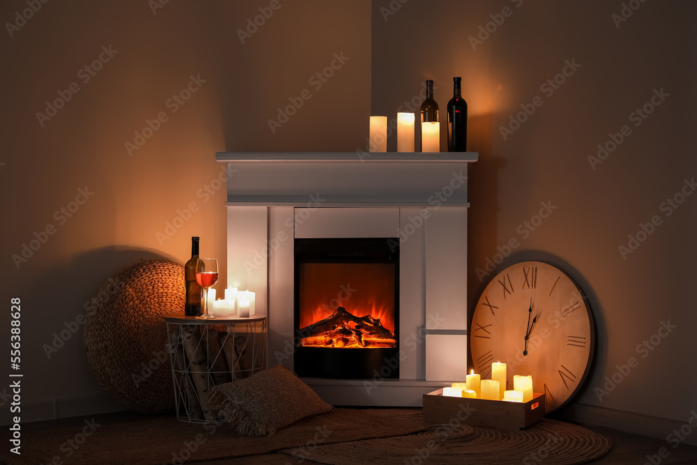 Interior of dark living room with fireplace, burning candles and wine