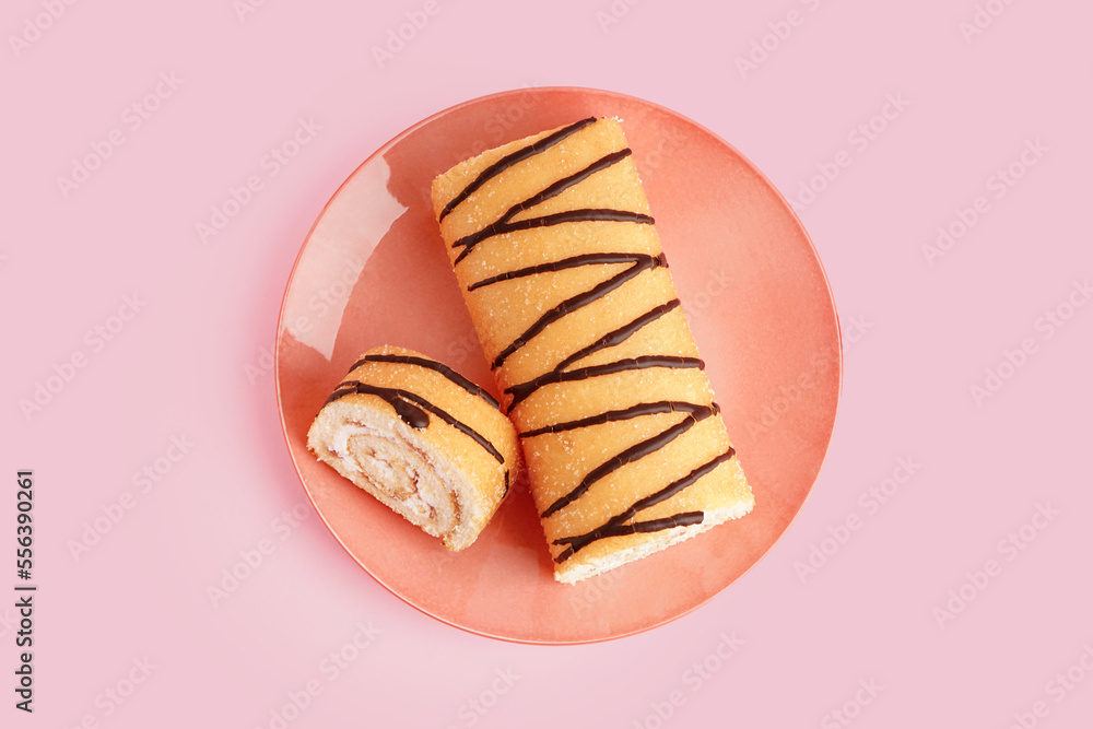 Plate with sweet sponge cake roll on pink background