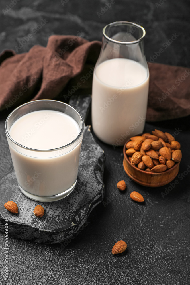 Glass, bottle of almond milk and nuts on dark background