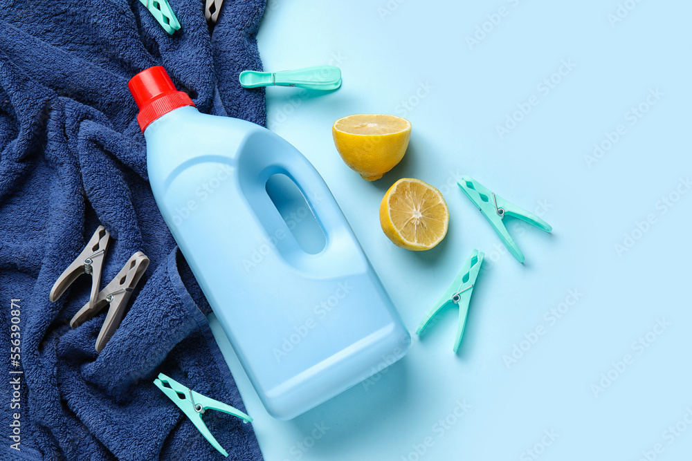 Laundry detergent, lemon and clothespins on blue background