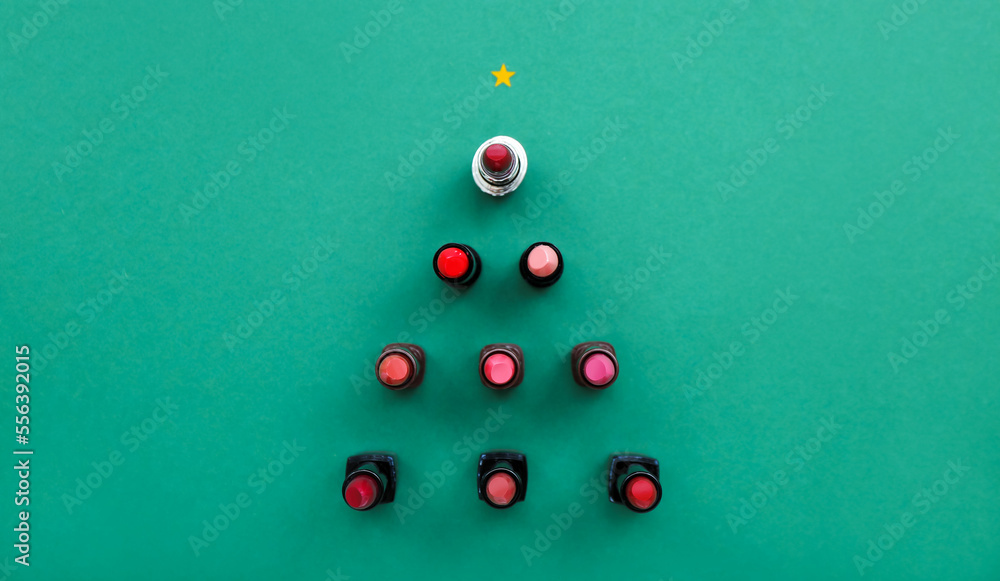 Christmas tree made of different lipsticks on green background