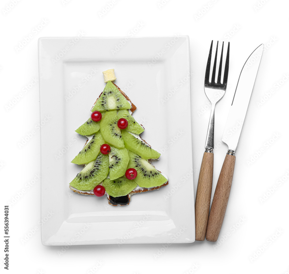 Plate of tasty pancake in shape of Christmas tree with fruits and cutlery on white background