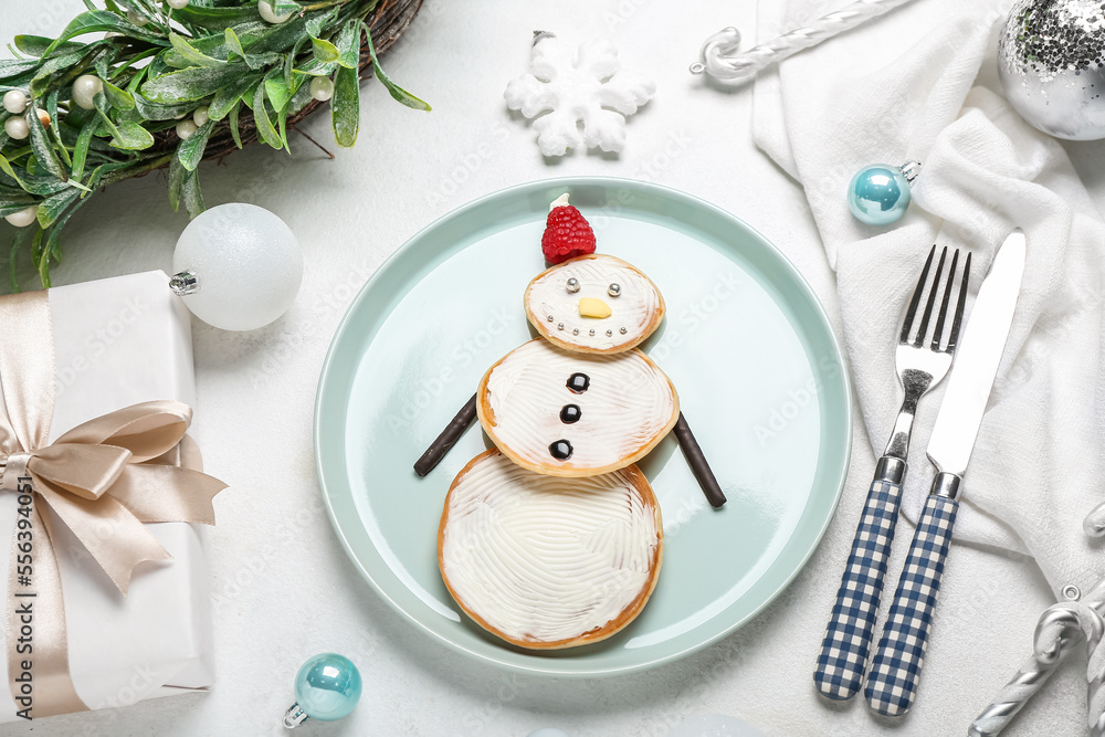 Composition with plate of tasty snowman pancakes, Christmas gift and decorations on light background