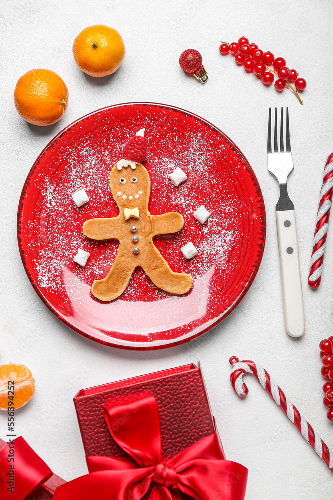 Plate with tasty gingerbread man, fruits and Christmas decor on light background