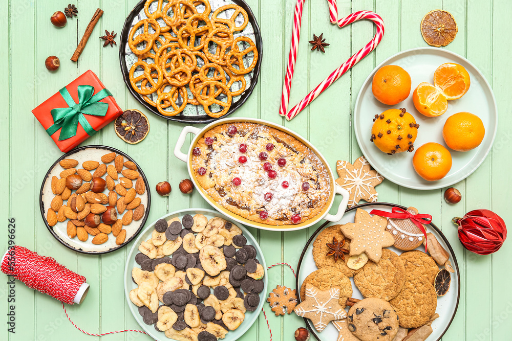 Christmas table setting with tasty pastries and fruits on green wooden background