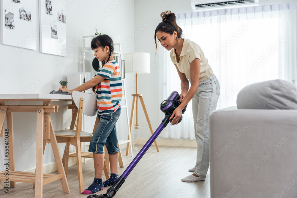 Caucasian beautiful mother cleaning house with young kid daughter.