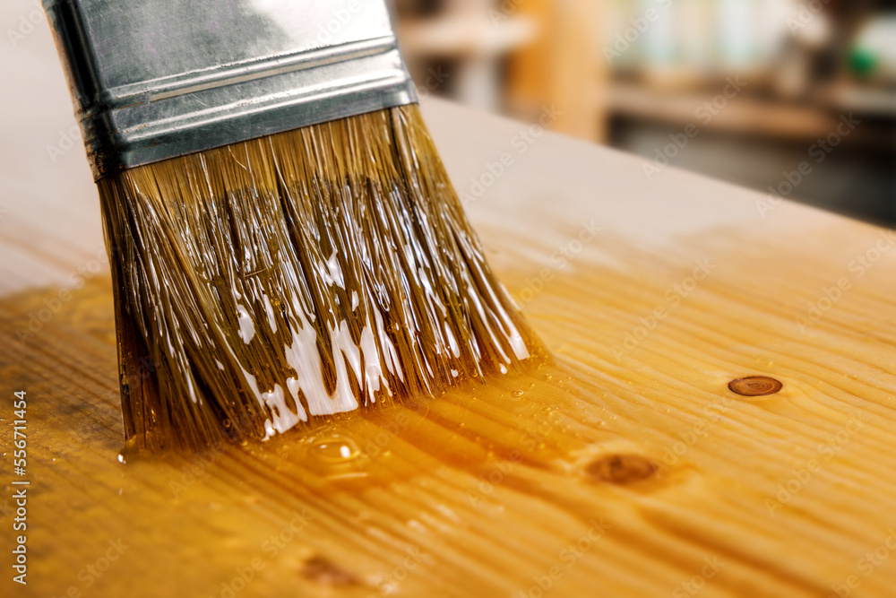 applying varnish on wooden board with paint brush. furniture coating and protection