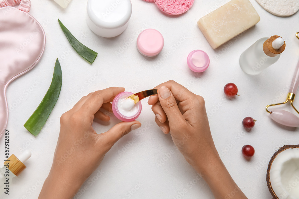 Female hands with jar of natural cream, essential oil and soap on light background