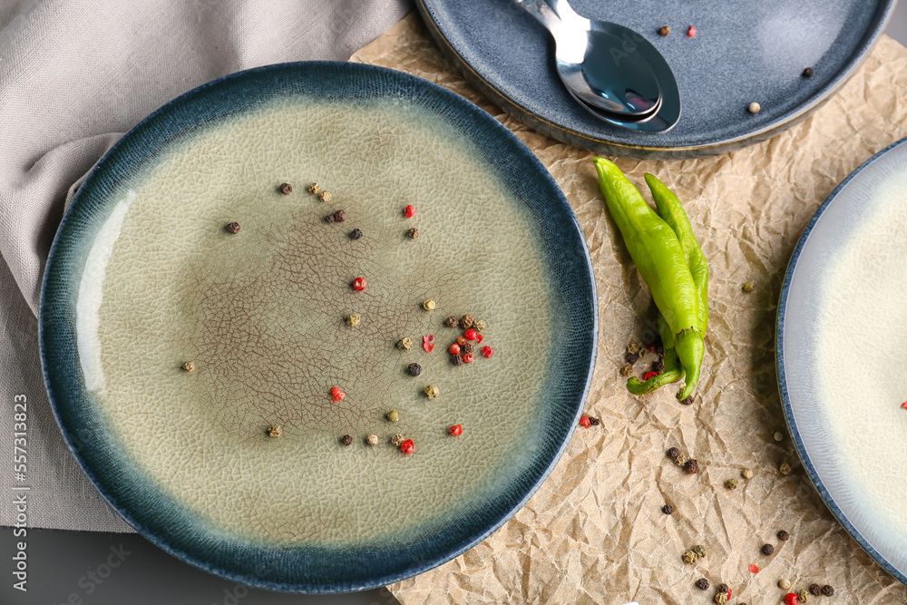 Different plates with peppercorns and spoon on table