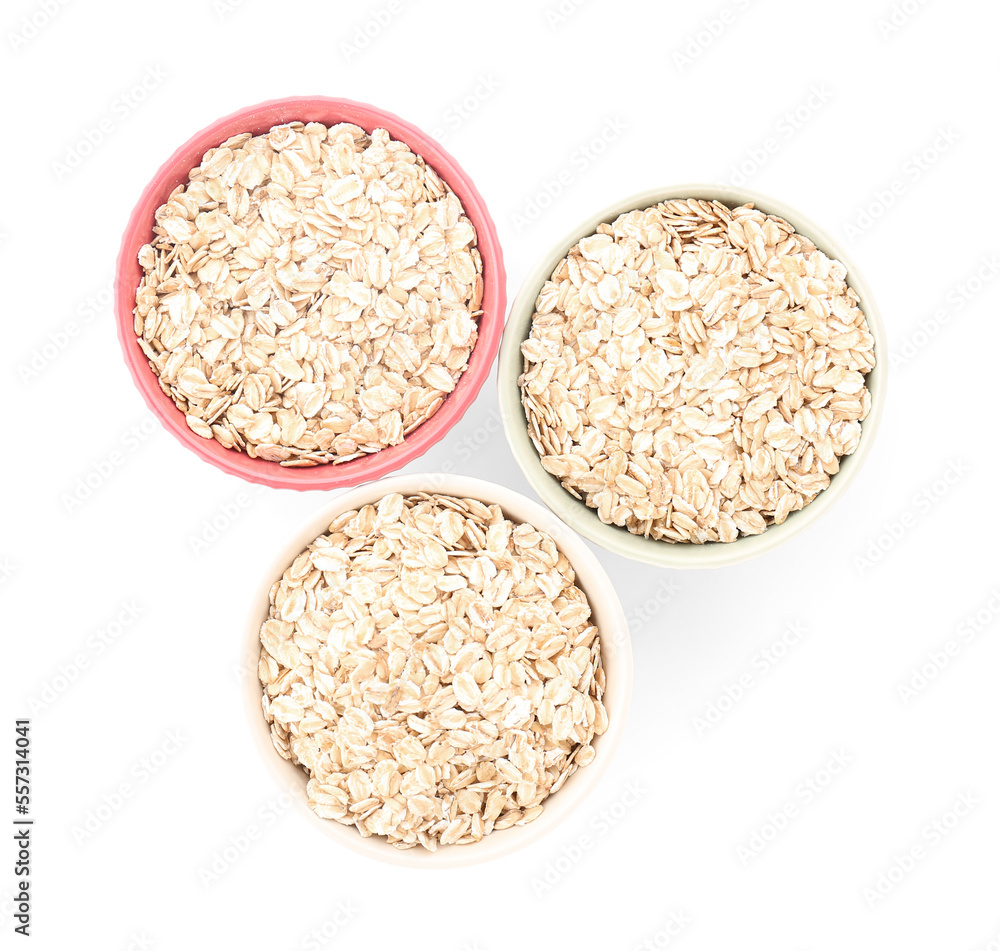 Bowls of raw oatmeal on white background