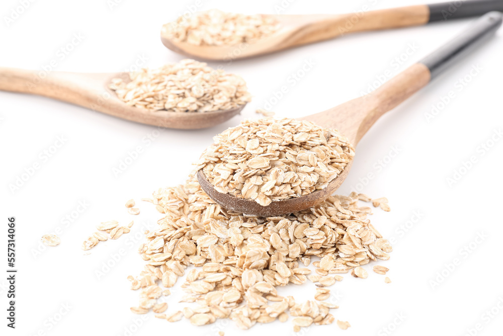 Wooden spoons with raw oatmeal on white background, closeup