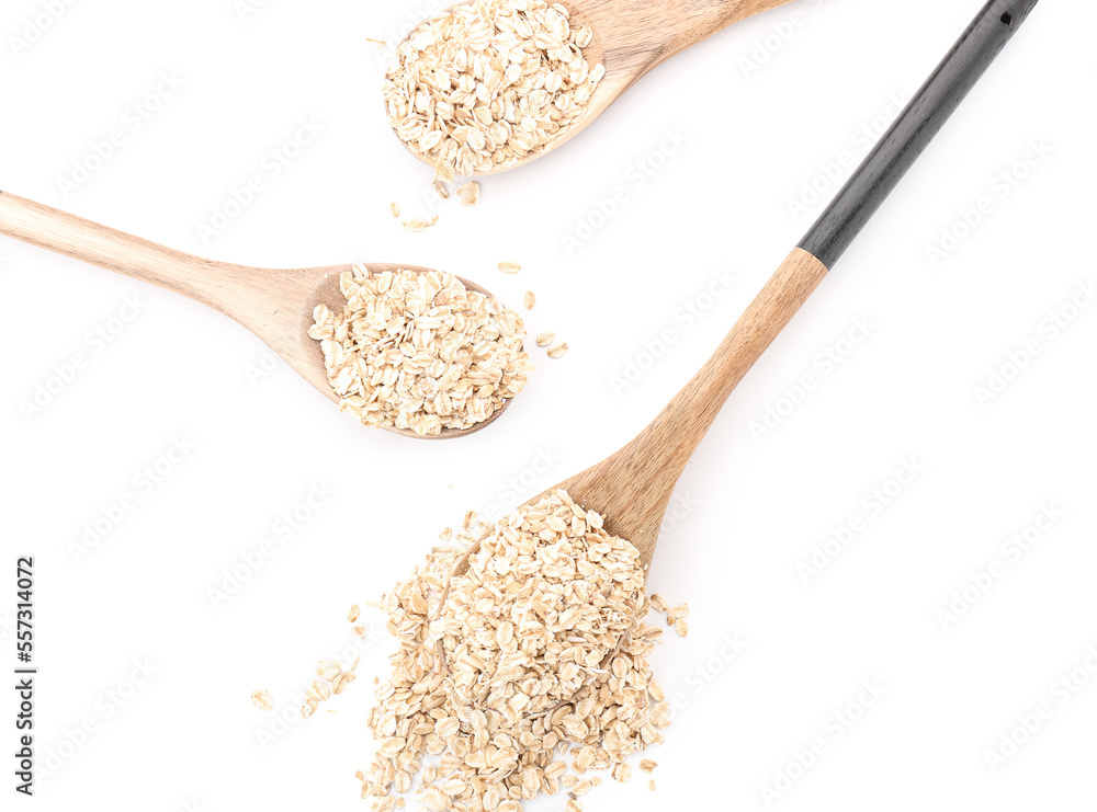 Wooden spoons with raw oatmeal on white background