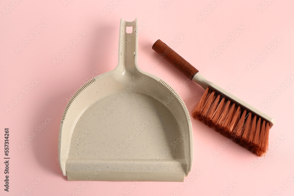 Dustpan and brush on pink background