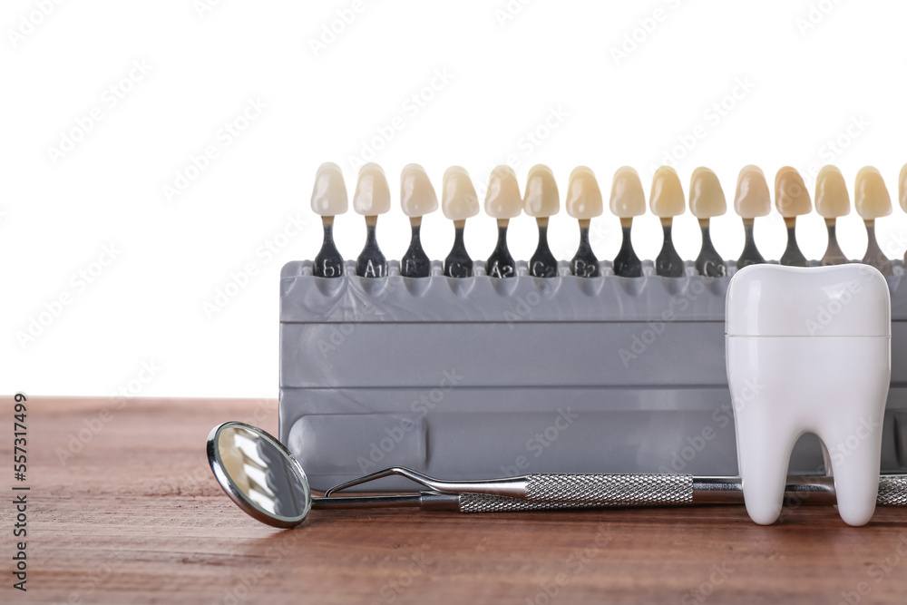 Teeth color samples with dental tools on table against white background