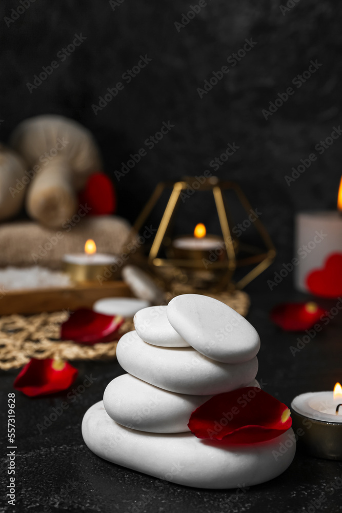 Spa stones with rose petals on dark table, closeup. Valentines Day celebration