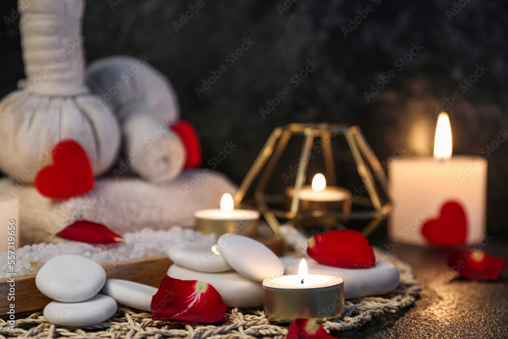 Spa stones with rose petals and candles on dark table, closeup. Valentines Day celebration