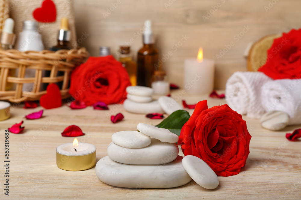 Spa stones with rose and candle on wooden table, closeup. Valentines Day celebration