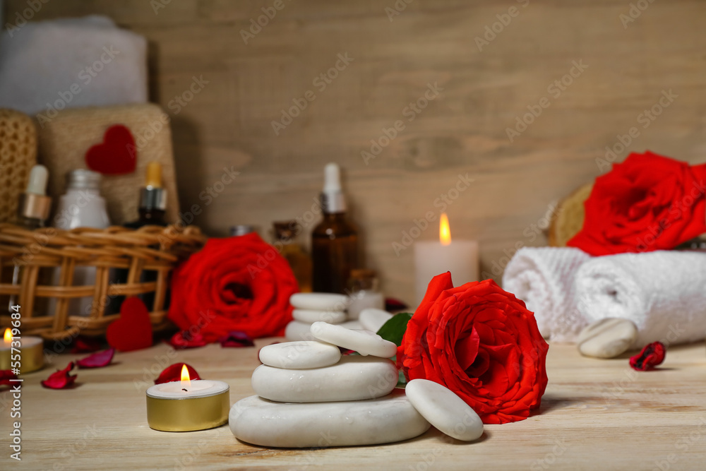 Spa stones with rose and candle on wooden table, closeup. Valentines Day celebration