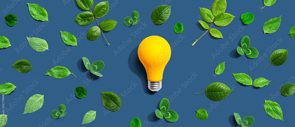 Yellow light bulb with green leaves - Flat lay