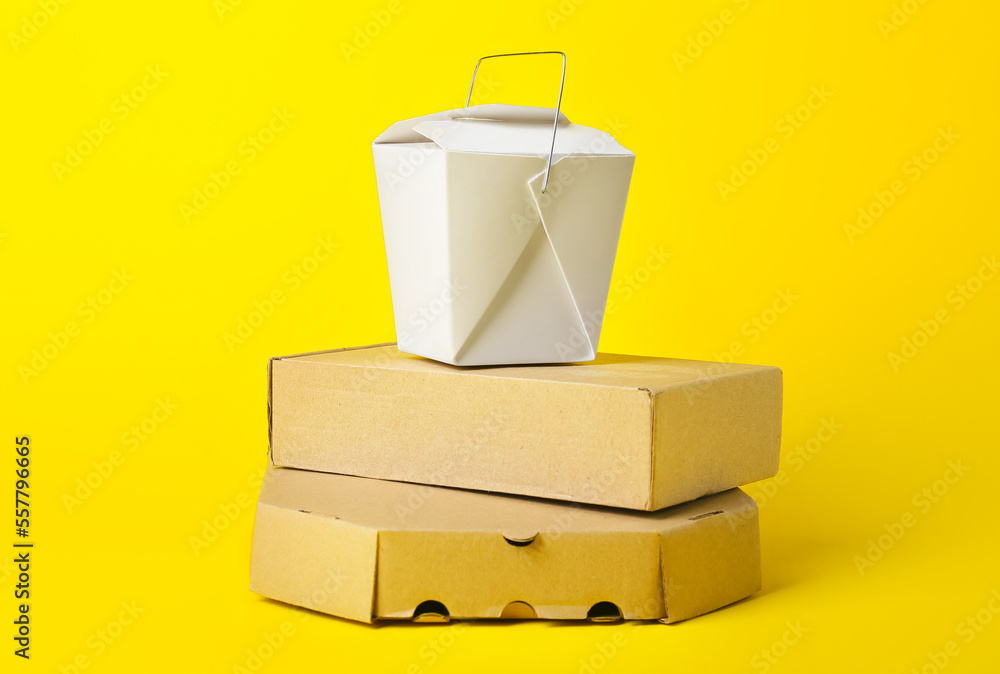 Stack of different food boxes on color background