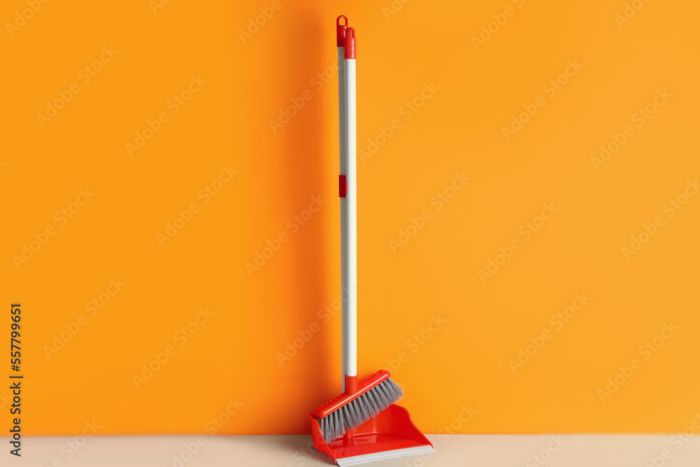 Dustpan with cleaning broom on floor near color wall