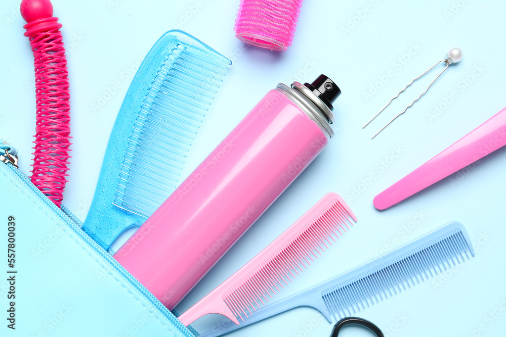 Bag with hair spray, combs and clips on blue background, closeup