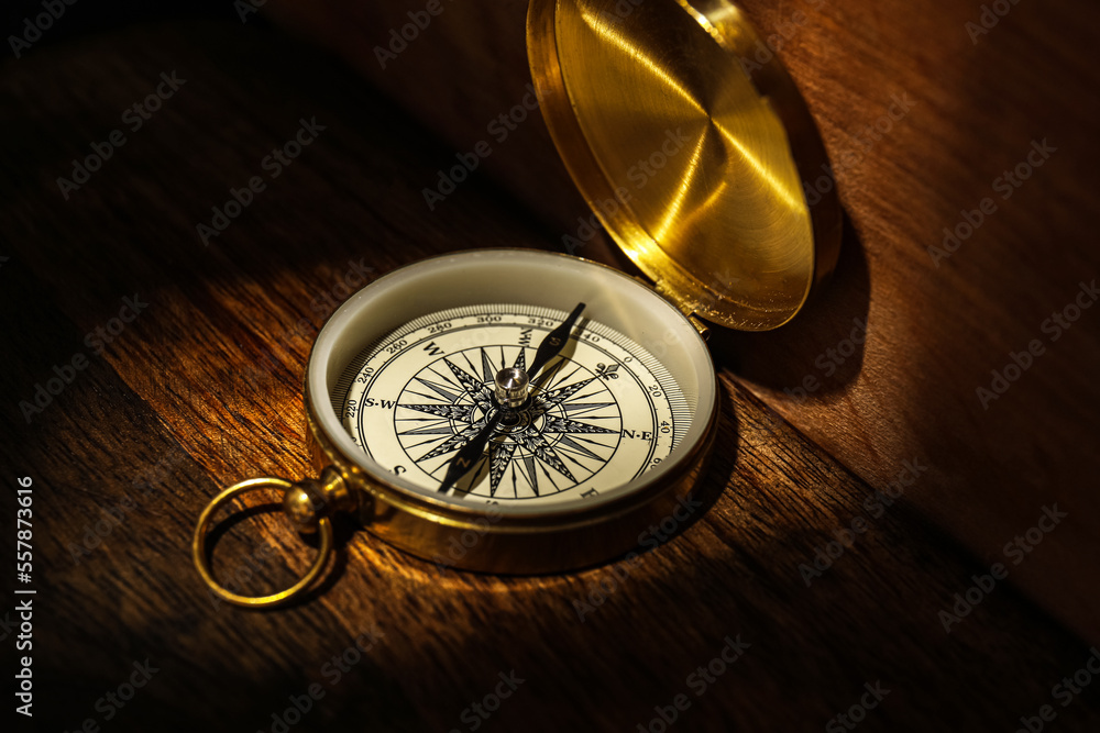 Golden compass on dark wooden background