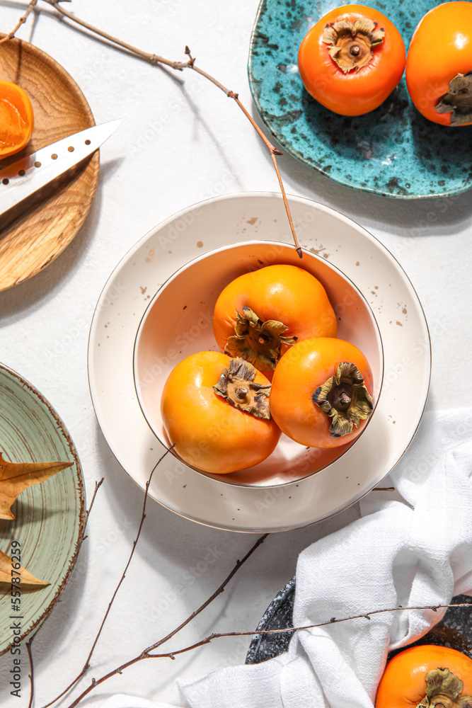 Plates with ripe persimmons on light background