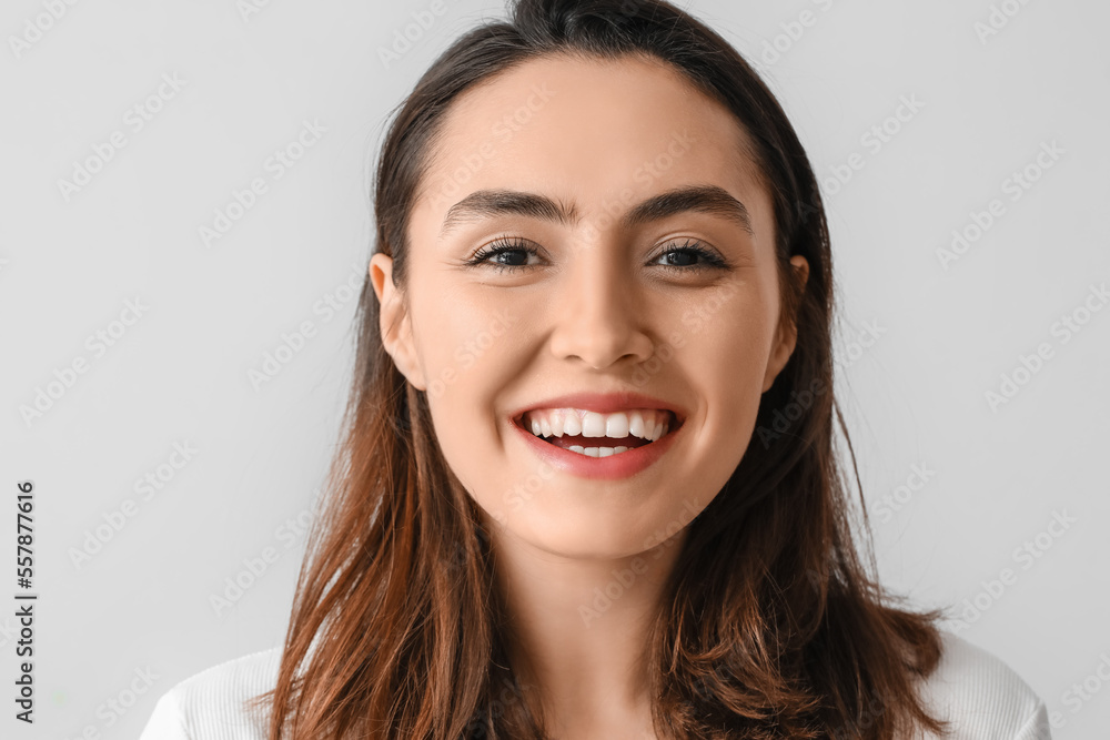 Young woman with beautiful smile on grey background, closeup