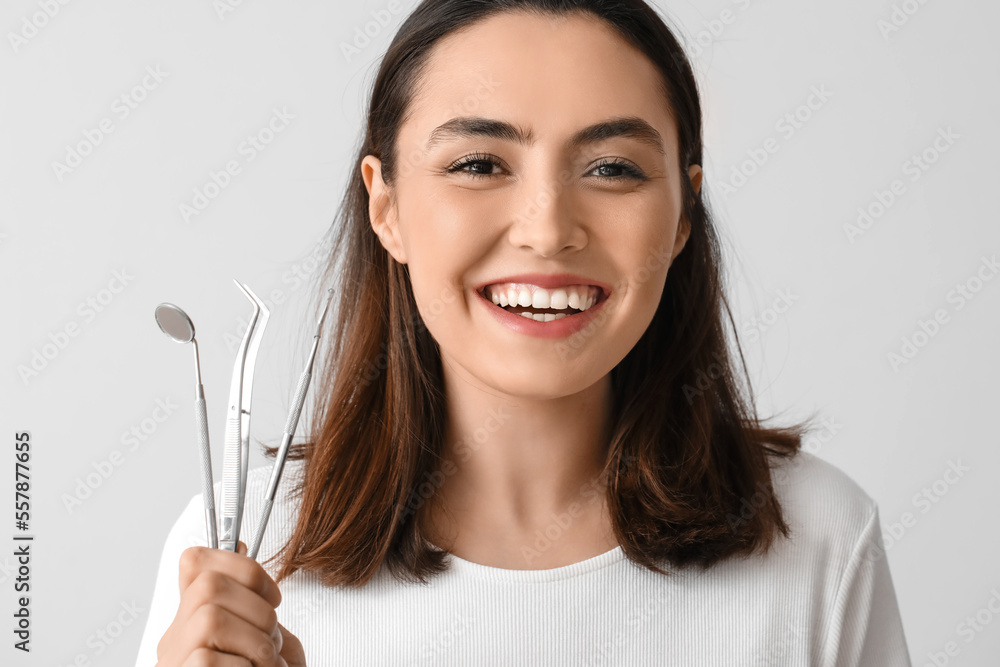 Young woman with dental tools on grey background, closeup