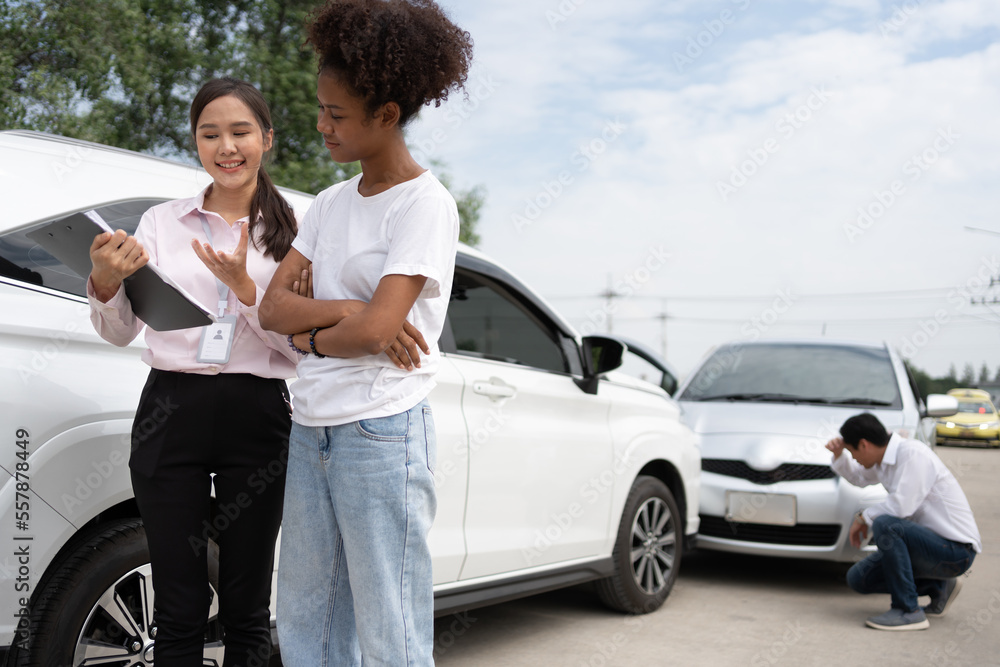 Women drivers Talk to Insurance Agent for examining damaged car and customer checks on the report cl